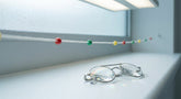 A Brock string with colored beads and prism flipper lenses arranged on a clean white surface under soft clinical lighting, representing vision therapy tools used in convergence insufficiency treatment.